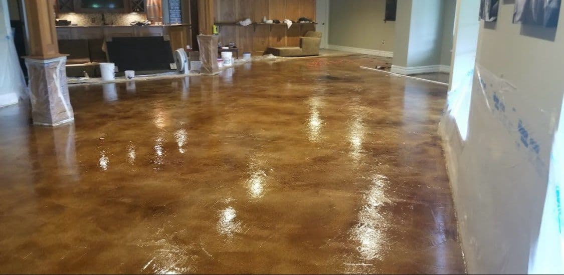 Glossy stained concrete floor in a renovated living room with construction materials.